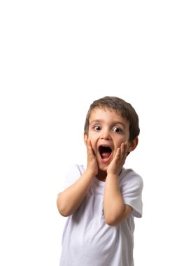 Beyaz tişört giyen 3 yaşında tatlı bir çocuk şaşırmış görünüyor, ağzı ve gözleri açık, elleri yanaklarında..