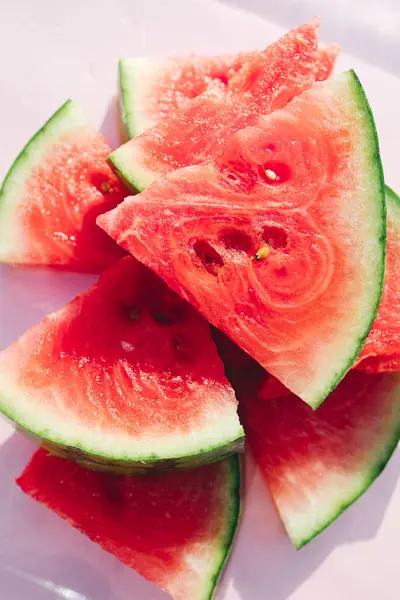 Pastel pembe arka planda taze karpuz dilimleri, en az yaz meyvesi konsepti.