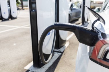 Bir şarj istasyonuna bağlı modern elektrikli araç, temiz enerji konsepti, sürdürülebilirlik, çevre dostu ulaşım ve gelecekteki hareketlilik