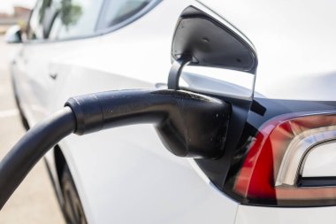 Bir şarj istasyonuna bağlı modern elektrikli araç, temiz enerji konsepti, sürdürülebilirlik, çevre dostu ulaşım ve gelecekteki hareketlilik