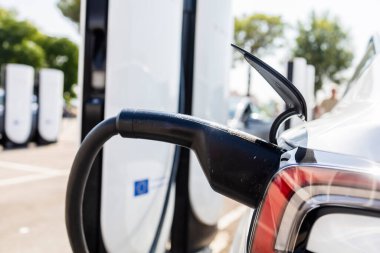 Bir şarj istasyonuna bağlı modern elektrikli araç, temiz enerji konsepti, sürdürülebilirlik, çevre dostu ulaşım ve gelecekteki hareketlilik