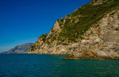 15 Nisan 2022-Amalfi kıyısı İtalya feribotundan deniz önü ve arka planda renkli evler ve mavi gökyüzü ile kıyı manzarası.