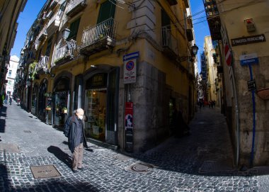 Nisan 04 2022 - Napoli İtalya - Kalabalık bir cadde Bir sürü scooterla ve insanlar eski renkli binaların önünden geçmek için yürüyorlar