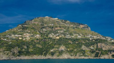 15 Nisan 2022-Amalfi Kıyısı İtalya güneşli bir günde feribottan çekilmiş ve kıyıda renkli evler görülmüştür.