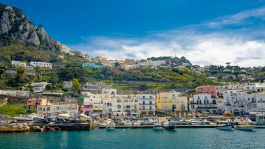 15 Nisan 2022-Capri İtalya feribot ve kıyı manzaralı arka planda renkli evler ve mavi gökyüzü.