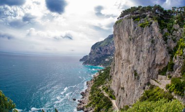 View from a cliff on the island of Capri, Italy, and rocks in the sea, blue sky and beautiful gardens
