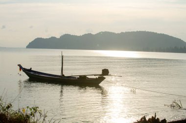 Fishing boat caught in the sunset silhouetted against the water and mountains in the background in Chumphon province Thailand