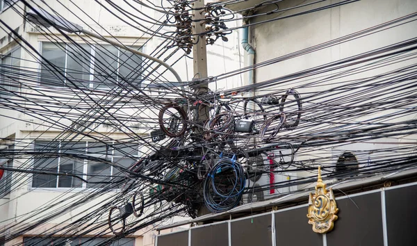 Direkte dağınık elektrik ve internet kabloları Tayland 'da bir elektrik direğindeki kablolar ve kablolar.