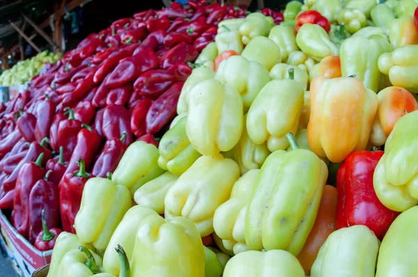 stock image Close-up on a stack of red, green and yellow bell peppers on a market stall.