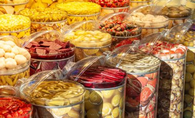 Pancar, sarımsak, biber gibi farklı renkte sebzelerle dolu büyük cam kavanozlar..