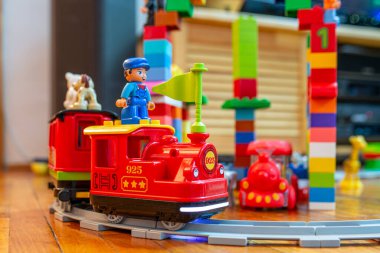 Aralık - 25 2024 - Bükreş Romanya-Arabalı kırmızı lokomotif ve küçük adamlar gri yolda ilerliyor