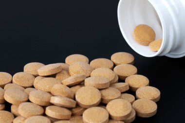 Haplar arka planda bir kutu hapın yanına saçılmış.