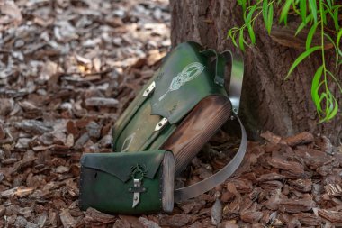 green leather bag-backpack with a purse, against the background of tree bark