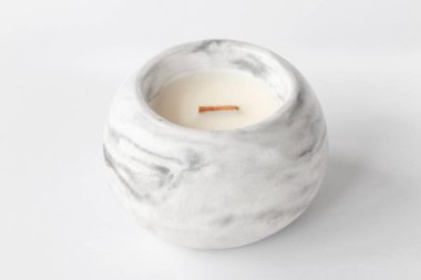 Alçıdan bir şamdandaki ahşap fitili olan kokulu mum, beyaz arka planda yakın plan.