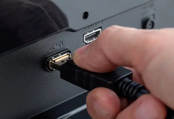 Bir elin bağlantı DP-IN 'ine bir Displayport kablosu takarken yakın plan görüntüsü. Ekran Portu kablosunu ekle