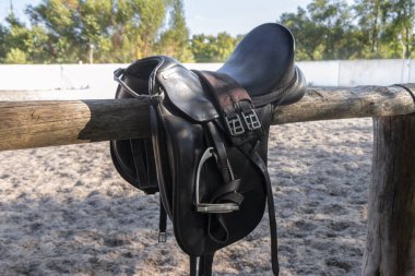Gösteri atlama yarışı için üzengilerle dolu deri bir eyer. Ata binmek için eyer. Kırsal çitte at eyeri. Binicilik sporu arka planı