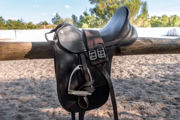 Gösteri atlama yarışı için üzengilerle dolu deri bir eyer. Ata binmek için eyer. Kırsal çitte at eyeri. Binicilik sporu arka planı