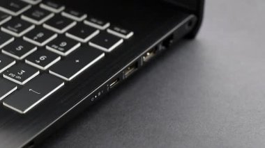 El bilgisayarı cihazlarla yüklemek ve senkronize etmek için USB tip C kablosunu laptopa bağlar. Beyaz kablo dizüstü bilgisayara bağlı. Yakın plan.