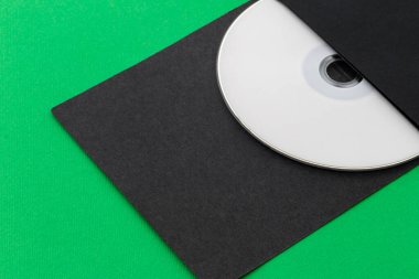 Beyaz CD, DVD, Blu Ray, Optik Disk, yeşil arkaplanda, siyah zarfın içinde.