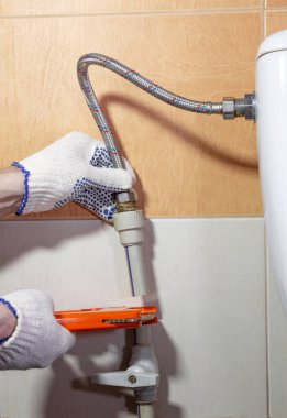 Su tesisatçısının elini kırmızı makasla kapat. Sarnıç suyu için eski polipropilen borusunu kes..