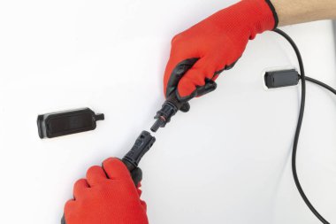 Güneş paneli sistemi kuran eldivenli teknisyen görüntüsü. Güneş paneli üzerinden Mc4 konnektörlerini bağlayan elleri kapatın. Yenilenebilir enerji kavramı.