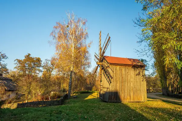 一个风景如画的秋天场景 其特点是在乡村风景中设置一个木制的风车 这张照片捕捉了蓝天下秋天树叶生机勃勃的色彩 — 图库照片