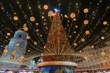 Ukrayna, Kyiv 'deki Aziz Sophia Meydanı' ndaki Noel ağacı ve ışıklarının büyüleyici manzarası. Aziz Sophia Katedrali 'nin çan kulesi şenlik sahnesi için görkemli bir zemin oluşturur.