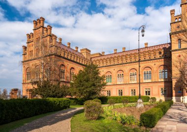 Manikürlü bahçelerle çevrili tarihi konutun çarpıcı tuğla mimarisi. Bina, bulutlu bir gökyüzü altında Bizans ve Fas tarzlarının bir karışımını sergiliyor.