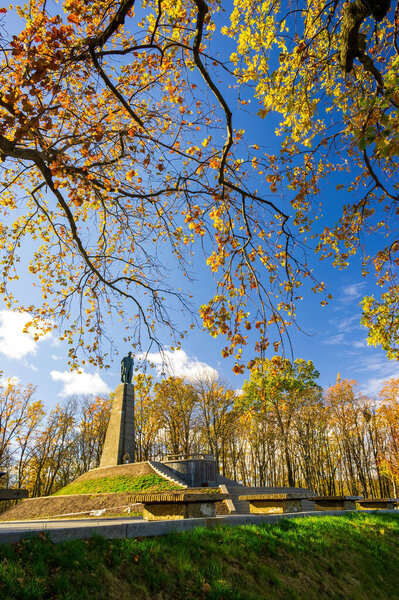Monument to Taras Shevchenko, Ukrainian poet, writer, artist, public and political figure, located on Chernecha Hill in Kaniv, Ukraine, surrounded by colorful autumn foliage under a bright blue sky