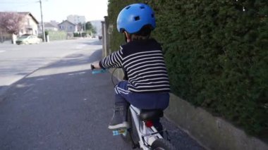 Avrupa 'da kaldırımda bisiklet süren bir çocuk. Küçük bir çocuk bisiklet şehir sokağına çıkıyor.