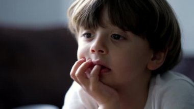 Küçük bir çocuk, el pençe divan kameradan ekranı seyrediyor. Odaklanmış çocuk TV medya içeriğiyle hipnotize edildi