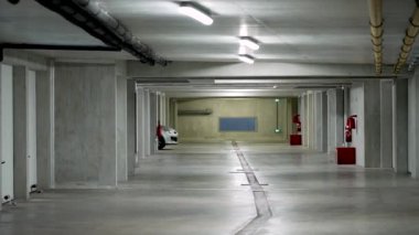 Beyaz gri bir araçla yeraltı otoparkından çıkan araba. Modern garaj iç mimarisi