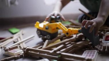 Çocuk buldozer traktör oyuncağıyla oynuyor. Oyun odasında odun topluyor. Kapalı çocuk elleri