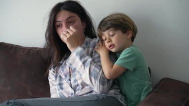 Sabahları koltukta oturan çocuğun annesine sevgi ve şefkat göstermesi. Otantik gerçek hayat anne ve çocuk bakımı ve kucaklaşması