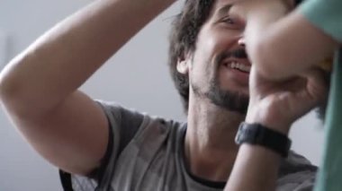 Çocuk şapkası takan adam. Oyuncu baba yün kış aksesuarı örüyor.