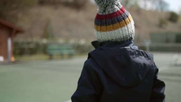 ビーニーとコートを着た子供の背中 冬の季節に子供は冬服を着る — ストック動画