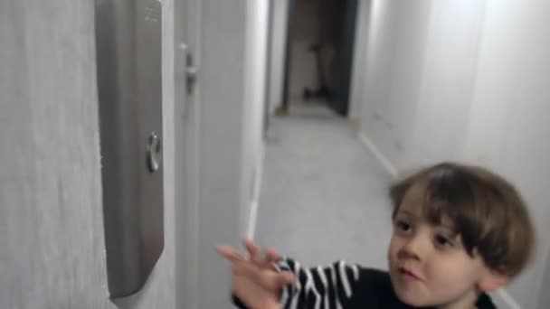 廊下に立ってエレベーターのボタンを押している男の子が一人いる 子供の手は垂直輸送を呼び出すボタンを押す — ストック動画