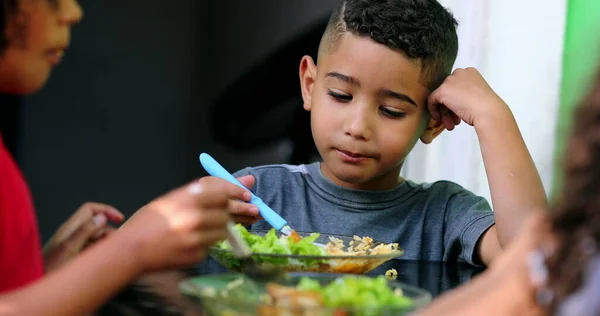 Brazilian children eating lunch together. Hispanic mixed race boy eats food