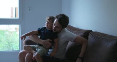 Çocuklar babalarının kucağına tırmanıyor kanepede kapalı yerlerde takılıyorlar. Samimi bir ebeveyn ve oğul ilişkisi