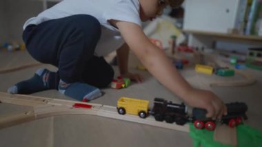 Çocuk odada oynuyor. Küçük bir çocuk tek başına oyuncaklarla oynuyor. Küçük çocuk yatak odasında demiryolu döşemesiyle