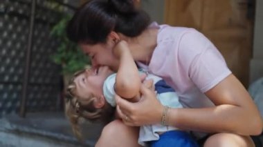 Anne çocuğu öpücükle örtüyor. Gerçek hayatta anne oğlunu öper. Otantik aşk ve sevgi