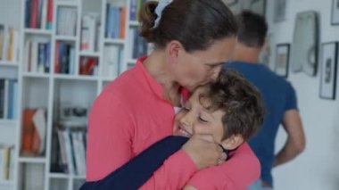 Anne oğlunu alnından öpüyor. Samimi anne, çocuk yavrularına sevgi ve şefkat gösteriyordu. Ebeveyn, çocuğu evde öper. otantik bakım