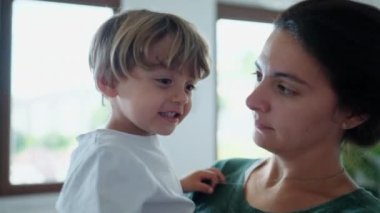 Anne kucağında çocuğu öpüyor ve kucağına alıyor. Samimi bir anne, genç bir çocuğa sevgi gösteriyor. Otantik gerçek annelik ilişkisi