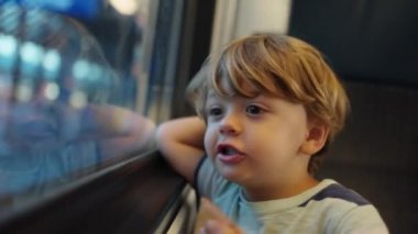 Pencere kenarında trenle seyahat eden küçük bir çocuk. İçerideki çocuk nakliye aracında. Yakından çocuk yüzü.