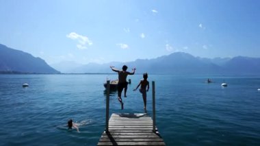 İnsanlar göle atlıyor. Baba ve oğlu İsviçre rıhtımında koşuyor ve Cenevre göl kenarına dalıyorlar. Ebeveynler ve çocuklar tatilde eğleniyor.