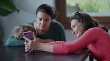 İçeride akıllı telefon cihazına bakan iki kadın. Samimi bayan arkadaşlar cep telefonu ekranını paylaşıyor çevrimiçi içeriği kontrol ediyorlar