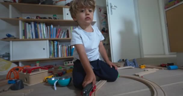 子供は部屋で遊ぶ 1人の小さな子供がおもちゃで遊んでいます 線路のある寝室の家の床の男の子 — ストック動画