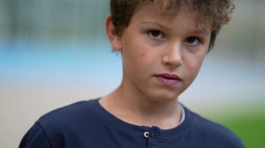 Dışarıda dikilip başını kameraya çeviren bir çocuğun portresi. Ergenlik öncesi erkek çocuk, yakın plan.