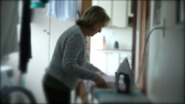 洗濯室で家事をするカジュアルシニア女性 — ストック写真