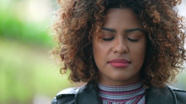 Siyah Afrikalı kadın, gözlerini kapatarak derin bir nefes alıyor.